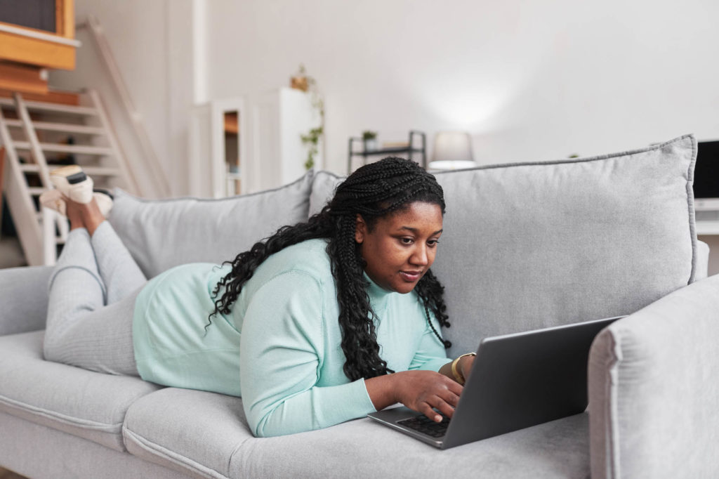 woman relaxes on her couch which using a laptop to sell glucose test strips