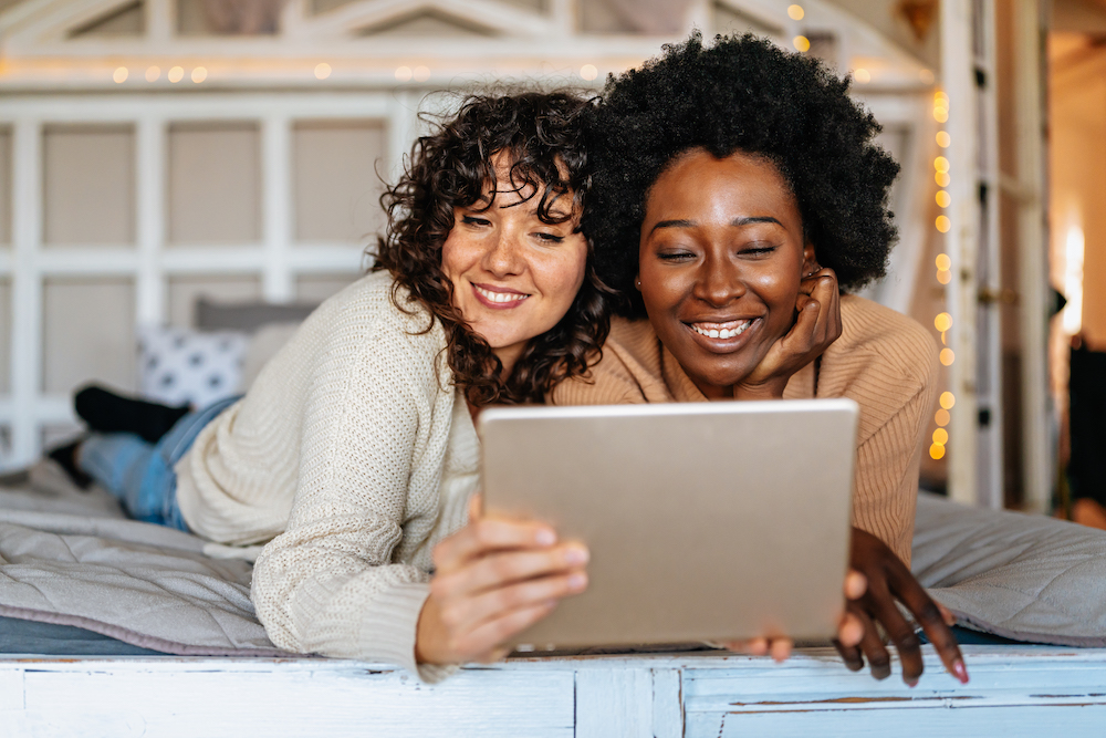 two women smile together looking at a tablet to sell glucose test strips