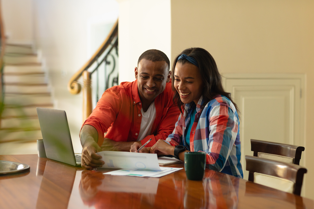 a young couple smiles while using their laptop to get cash for diabetic test strips