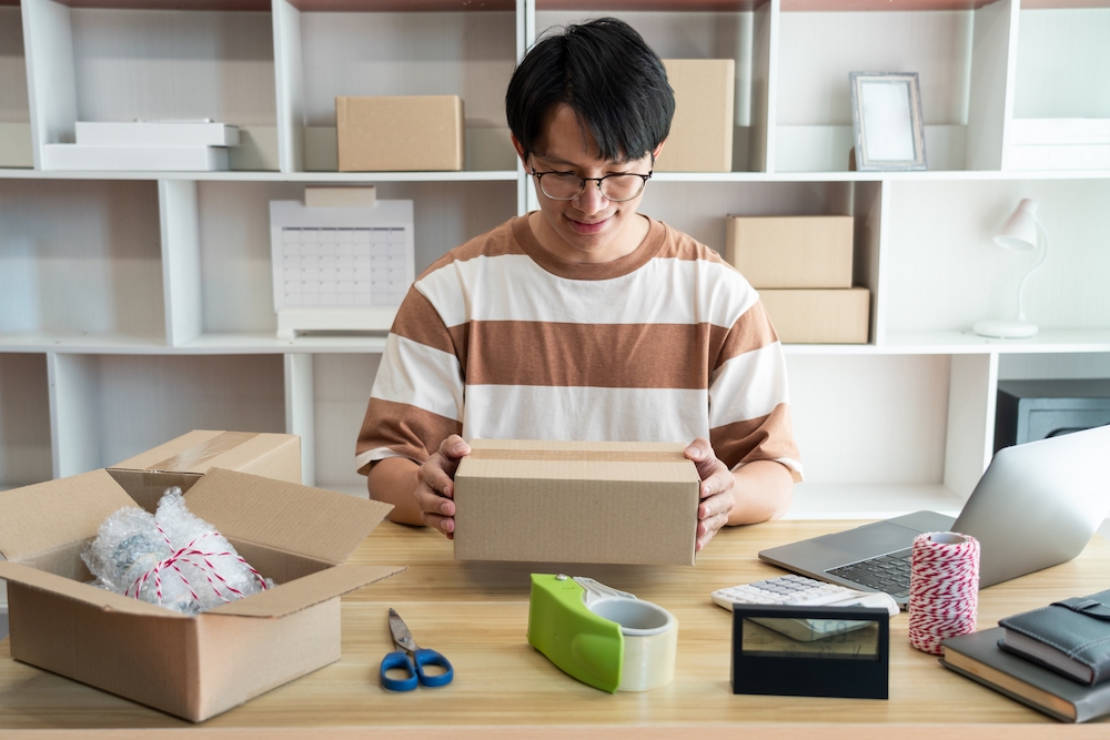 a young man with glasses prepares to ship a box to get cash for diabetic test strips