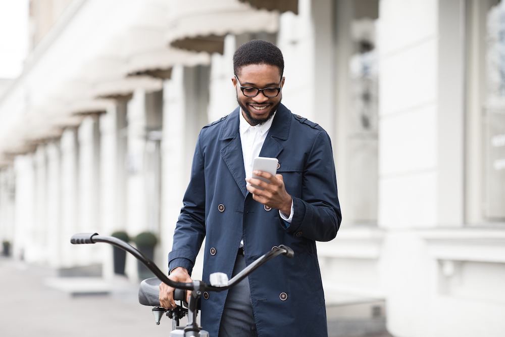 smiling young man on a bike smiles at his phone after getting cash for diabetic test strips