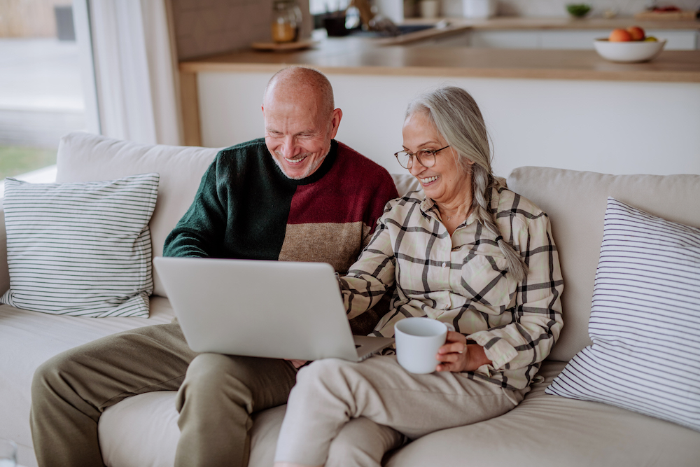 A senior couple smiles a they use their laptop to learn to sell freestyle diabetes test strips
